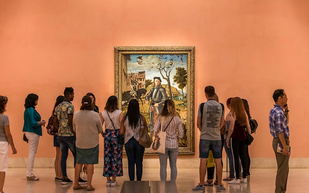 Visitors viewing a painting at Prado Museum, part of Paseo del Arte 3-Museum Pass in Madrid.