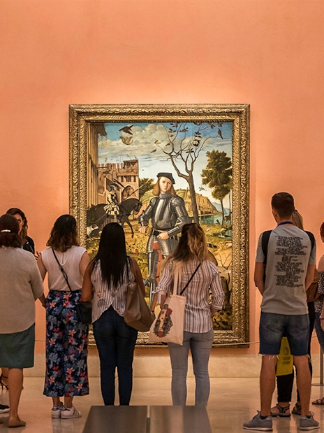 Visitors viewing a painting at Prado Museum, part of Paseo del Arte 3-Museum Pass in Madrid.