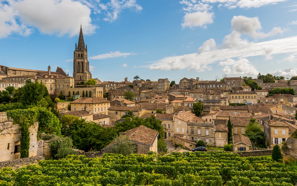 Saint Emilion village with vineyards and church tower under blue sky.