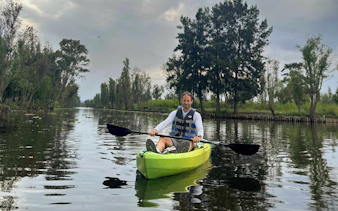 Kayaker paddling through Xochimilco canals with lush greenery in the background.