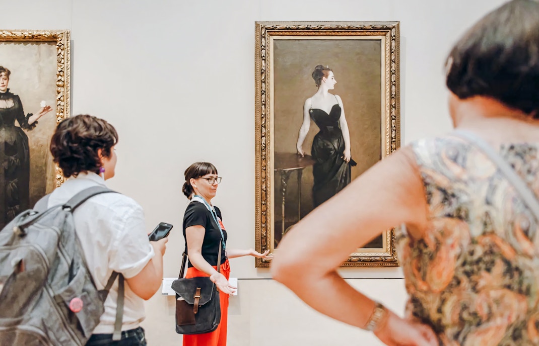 Visitors at the Metropolitan Museum of Art viewing John Singer Sargent's Portrait of Madame X with a tour guide.