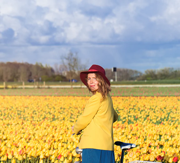 Woman with bicycle in a tulip field near Amsterdam.