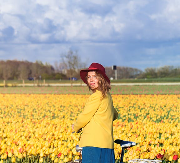 Woman with bicycle in a tulip field near Amsterdam.