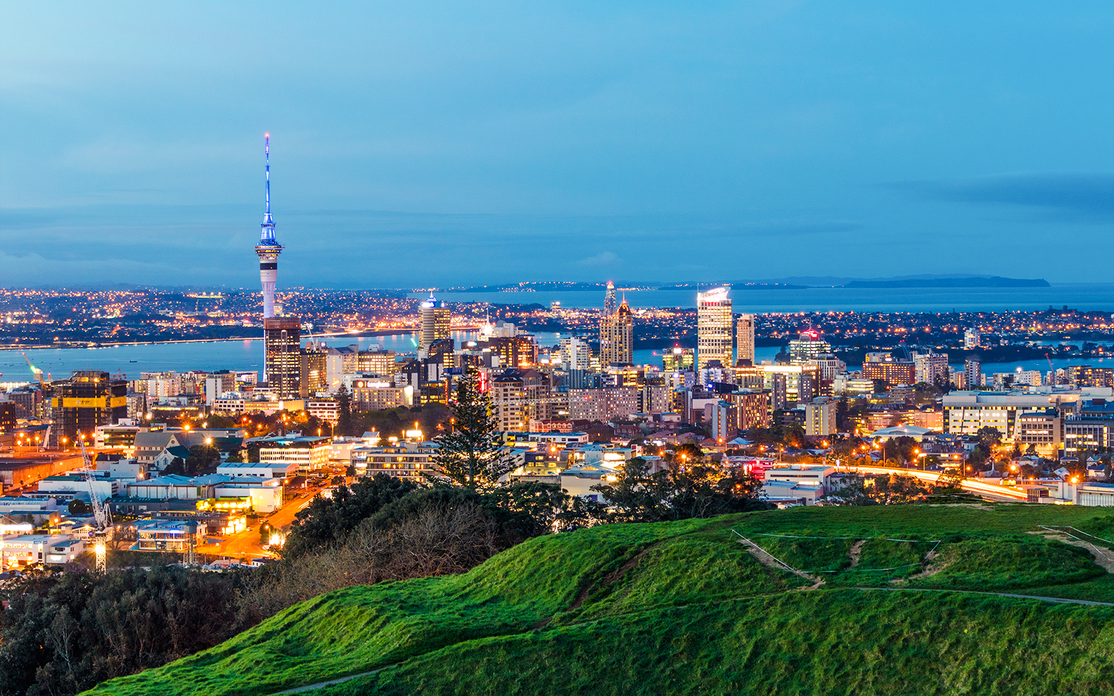 Auckland skyline at evening with Sky Tower and city lights.
