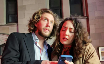 Couple using a smartphone for the Ghost of Wall Street self-guided city exploration game in Downtown New York.