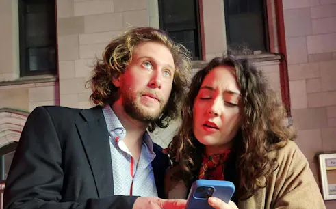 Couple using a smartphone for the Ghost of Wall Street self-guided city exploration game in Downtown New York.