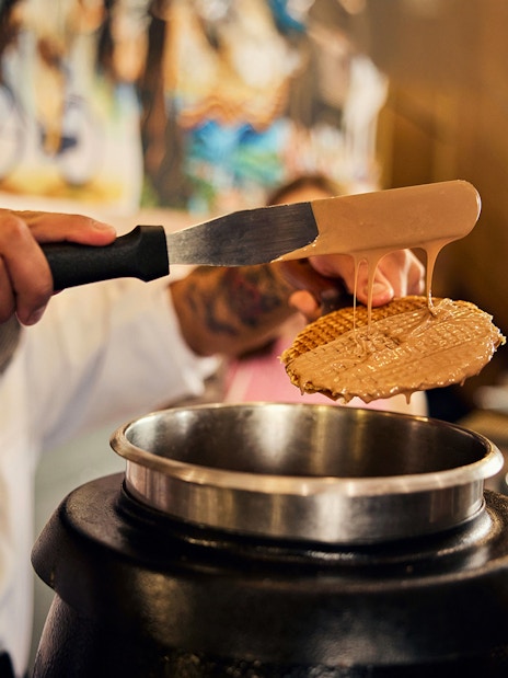 Waffle being coated with caramel at Dutch Waffle Making Workshop.