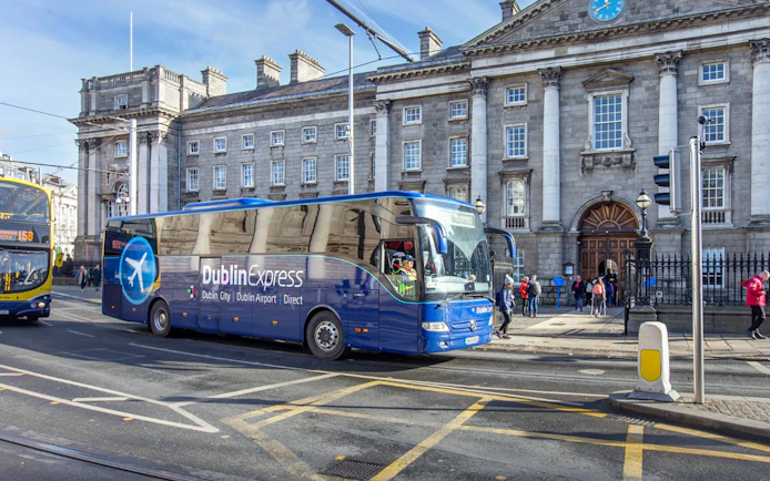 Dublin Express bus in front of historic building, offering one-way tickets from Belfast to Dublin Airport.