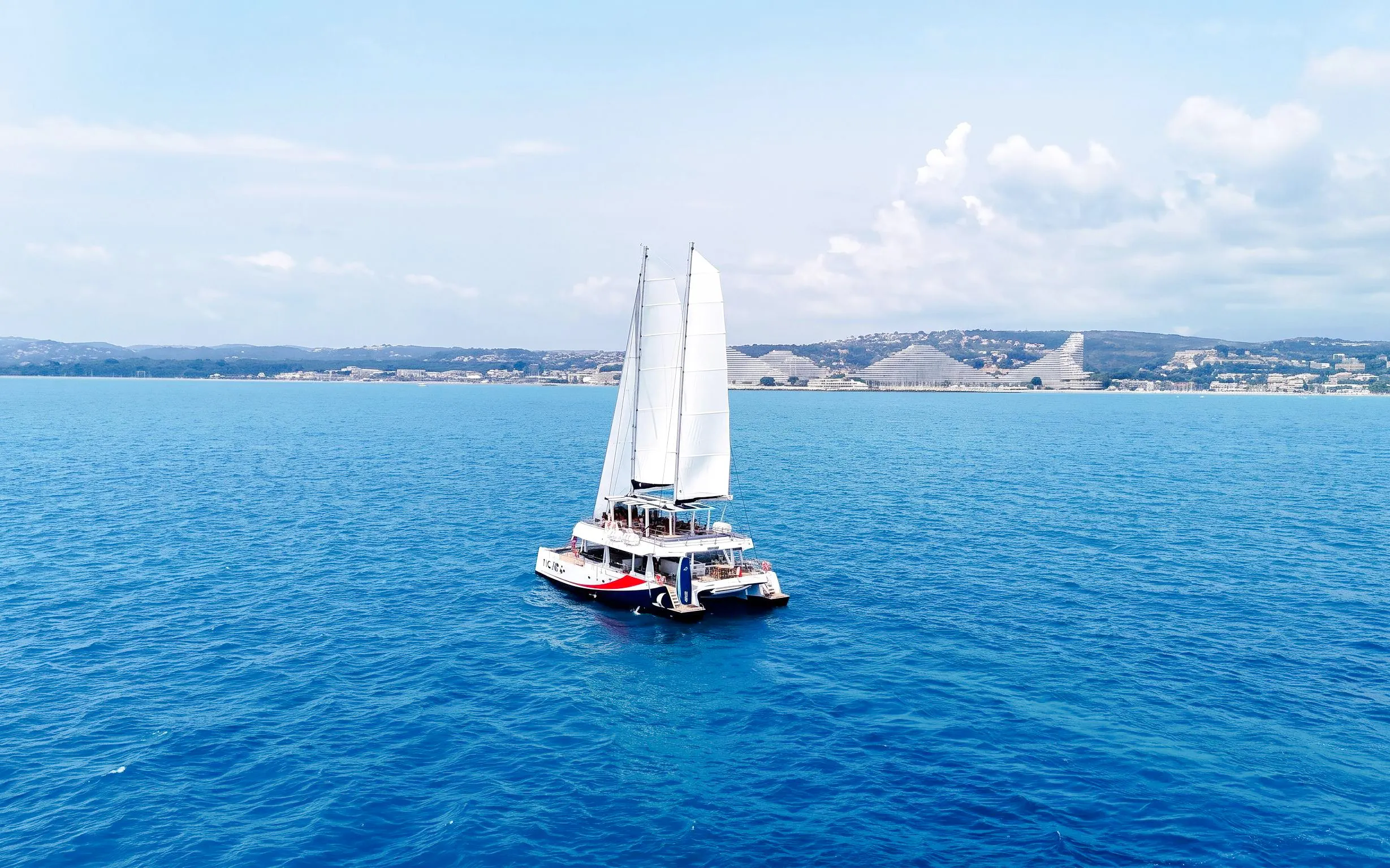 Catamaran sailing near Lérins Island with coastal view in Marina Bay of Angels.