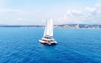 Catamaran sailing near Lérins Island with coastal view in Marina Bay of Angels.