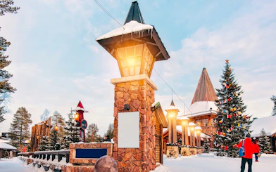 Santa Claus Village entrance with Christmas tree and visitors in Rovaniemi.