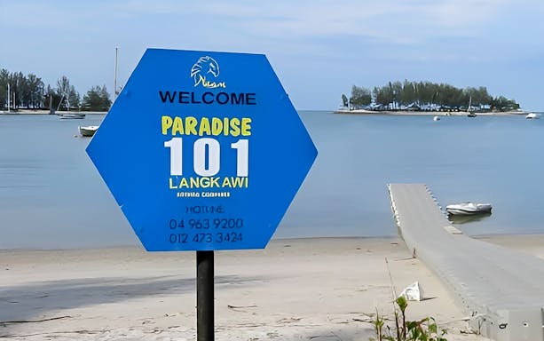 Welcome sign for Paradise 101, Langkawi, with a view of the island and dock.