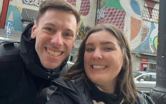 Couple smiling in front of colorful street art in Madrid during self-guided city exploration game.