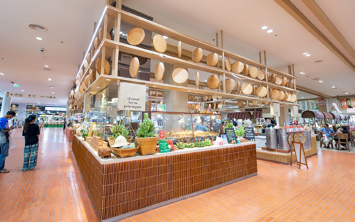 Food stall with wooden decor at Ayutthaya Floating Market, showcasing local produce and snacks.