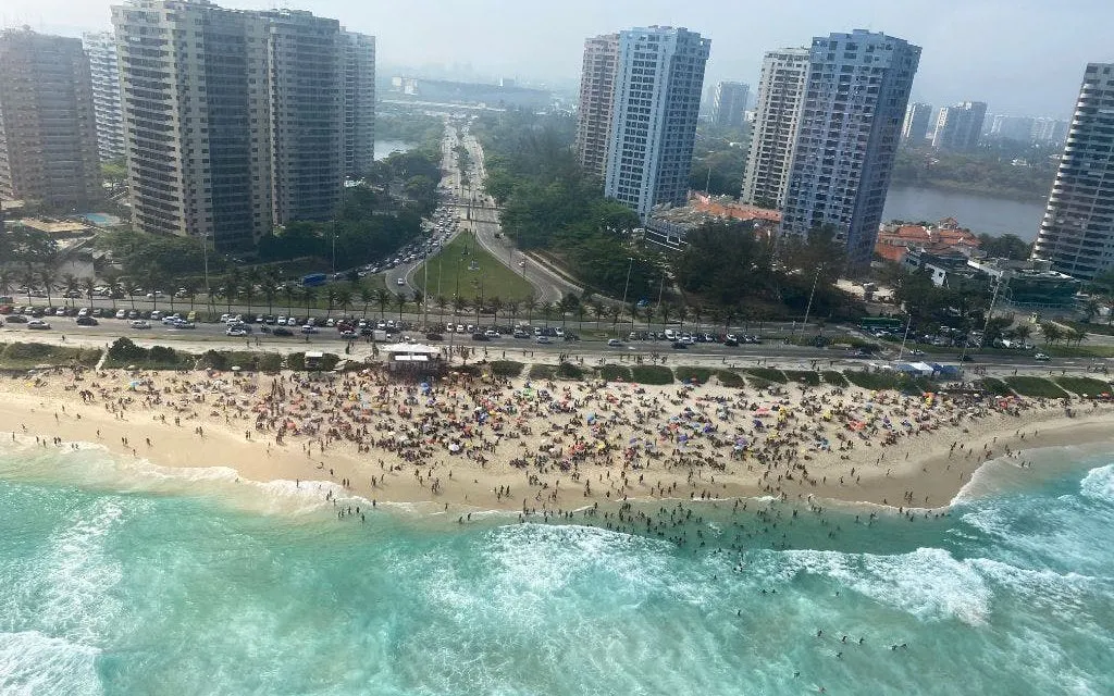 Aerial view of crowded Rio de Janeiro beach with high-rise buildings during VIP helicopter tour.