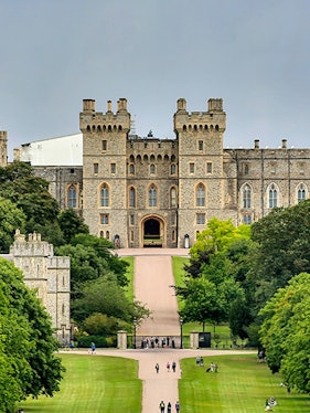Windsor Castle entrance with visitors on the path, surrounded by lush greenery.