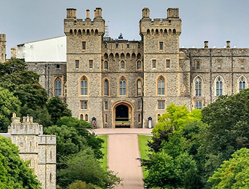 Windsor Castle entrance with visitors on the path, surrounded by lush greenery.