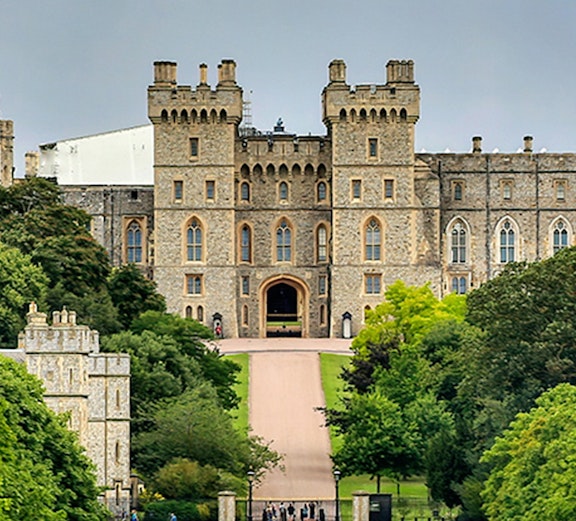 Windsor Castle entrance with visitors on the path, surrounded by lush greenery.