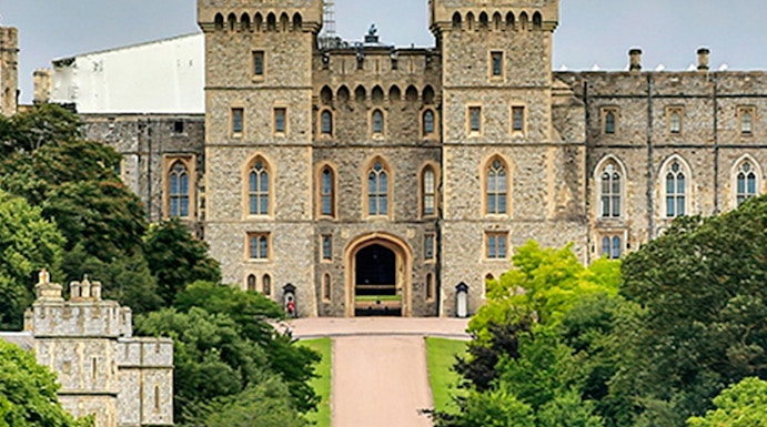 Windsor Castle entrance with visitors on the path, surrounded by lush greenery.