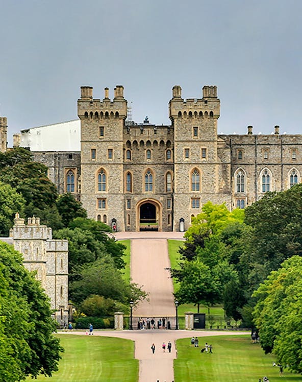 Windsor Castle entrance with visitors on the path, surrounded by lush greenery.