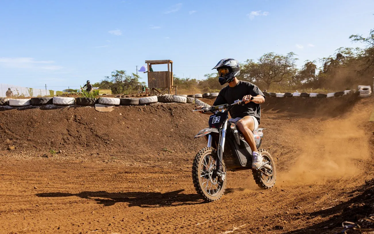 Rider on electric dirt bike navigating track in Oahu with expert guidance.