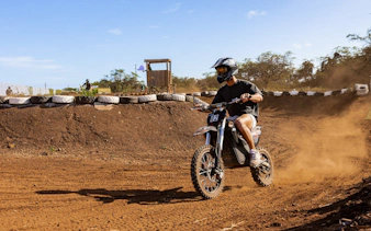 Rider on electric dirt bike navigating track in Oahu with expert guidance.