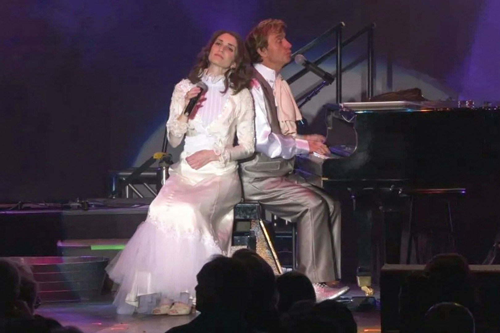 Performers on stage during Carpenters Legacy show, with one singing and the other playing piano.