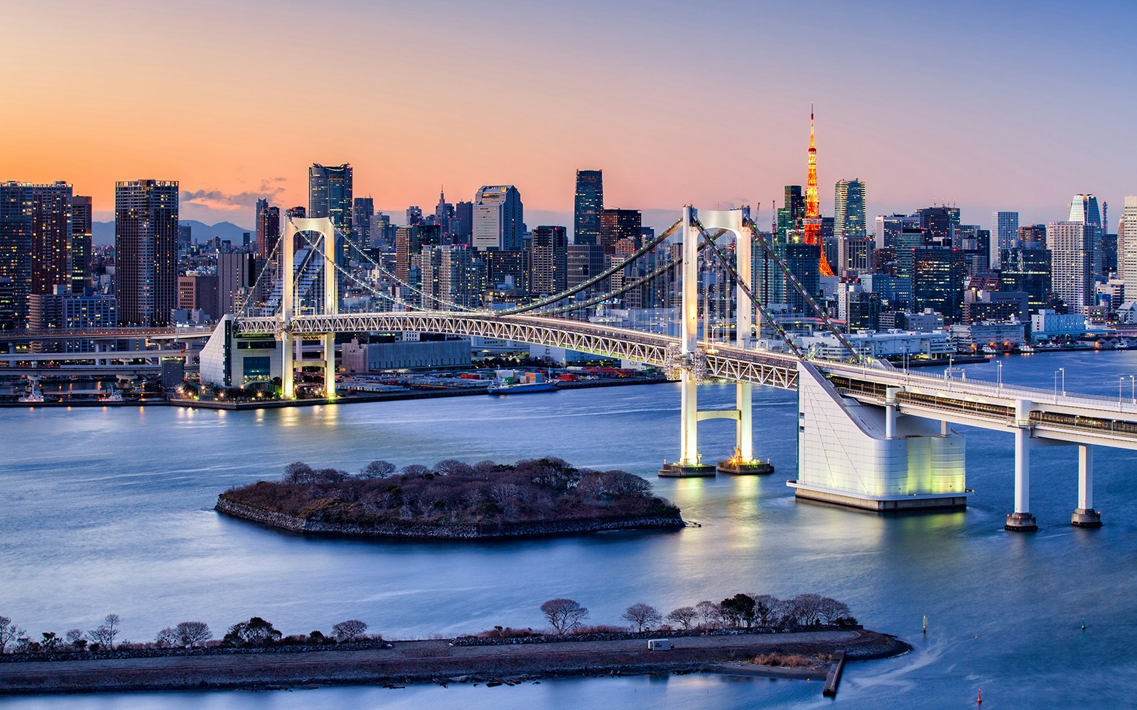 Rainbow Bridge spanning Tokyo Bay with city skyline at dusk.