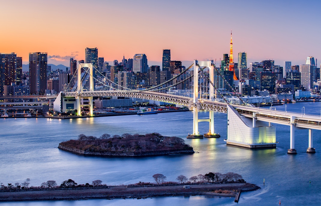 Rainbow Bridge spanning Tokyo Bay with city skyline at dusk.