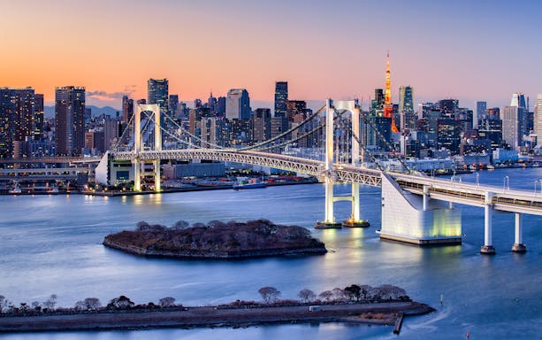 Rainbow Bridge spanning Tokyo Bay with city skyline at dusk.