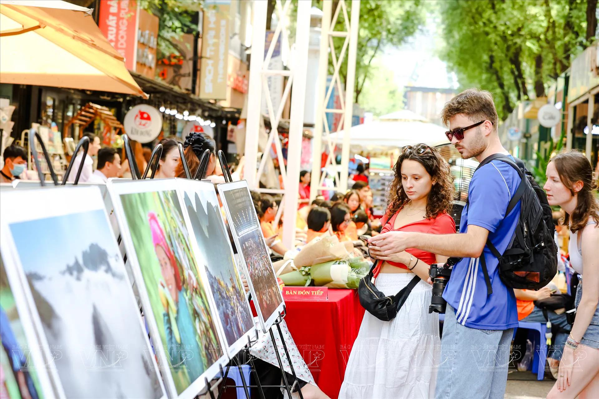 Tourists viewing art displays on a bustling street in Ho Chi Minh City.
