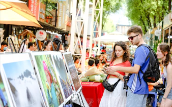 Tourists viewing art displays on a bustling street in Ho Chi Minh City.