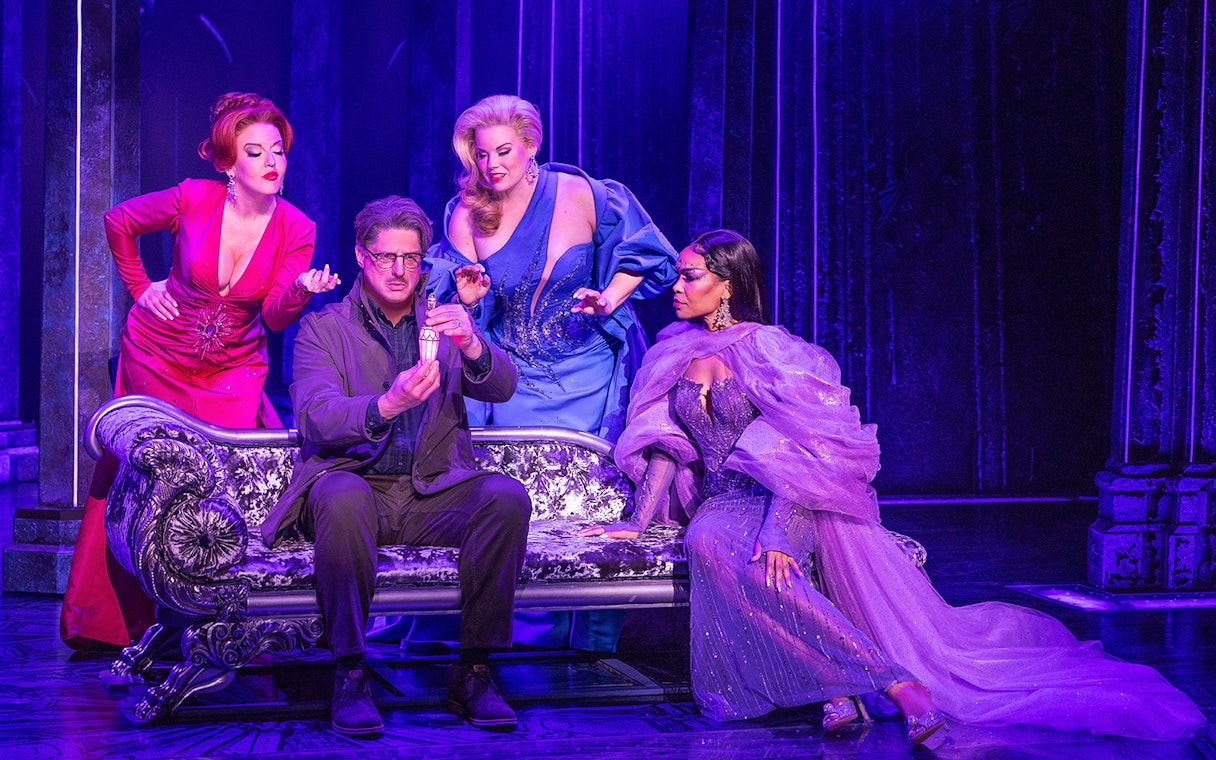 Four actors in colorful costumes on stage in a scene from "Death Becomes Her" musical.