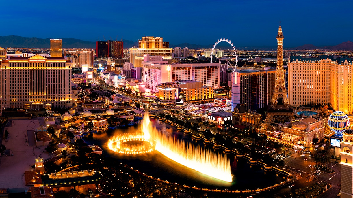 Las Vegas Strip at night with Bellagio fountains and Eiffel Tower replica.