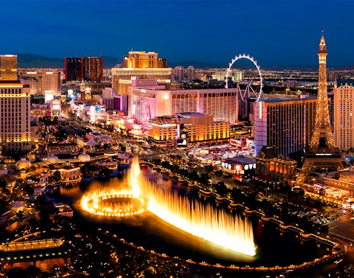 Las Vegas Strip at night with Bellagio fountains and Eiffel Tower replica.
