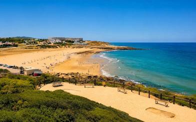 Achakar Beach with visitors enjoying the sandy shore and clear blue water in Tangier, Morocco.