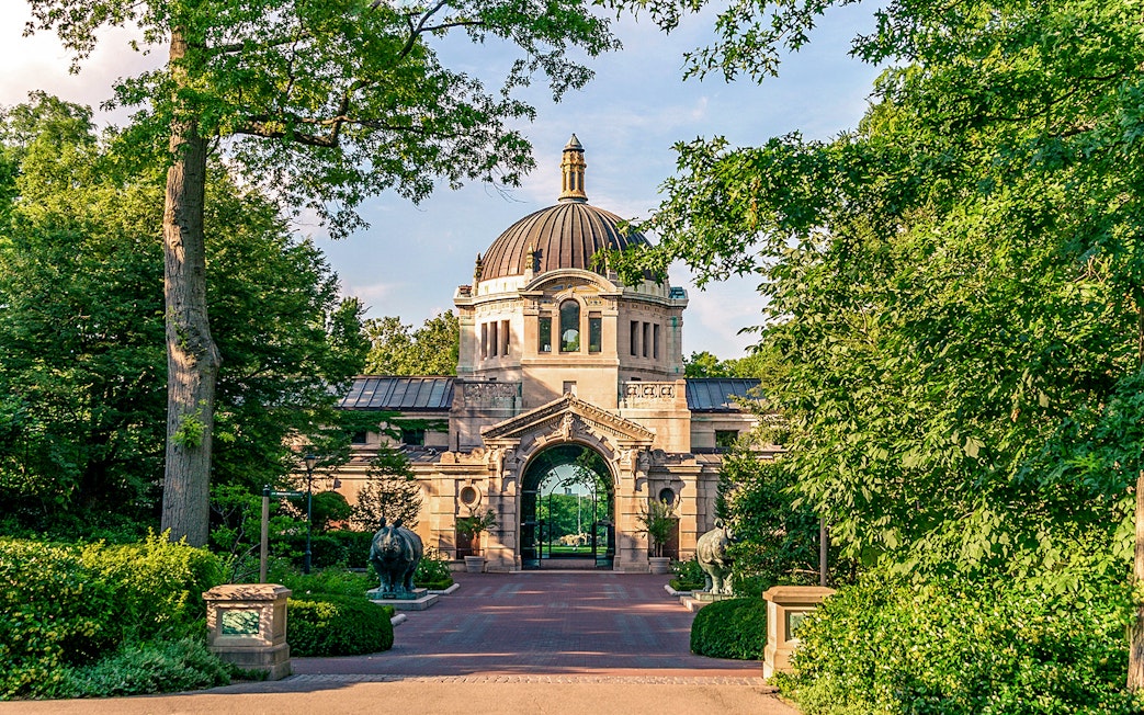 Entrance to the Bronx Zoo with ornate archway and lush greenery, New York.