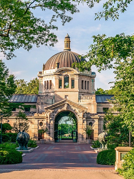 Entrance to the Bronx Zoo with ornate archway and lush greenery, New York.
