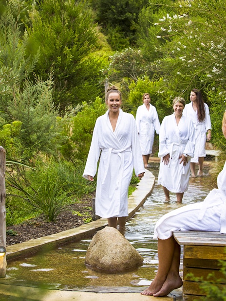 Visitors in white robes walking through a reflexology path at Peninsula Hot Springs.