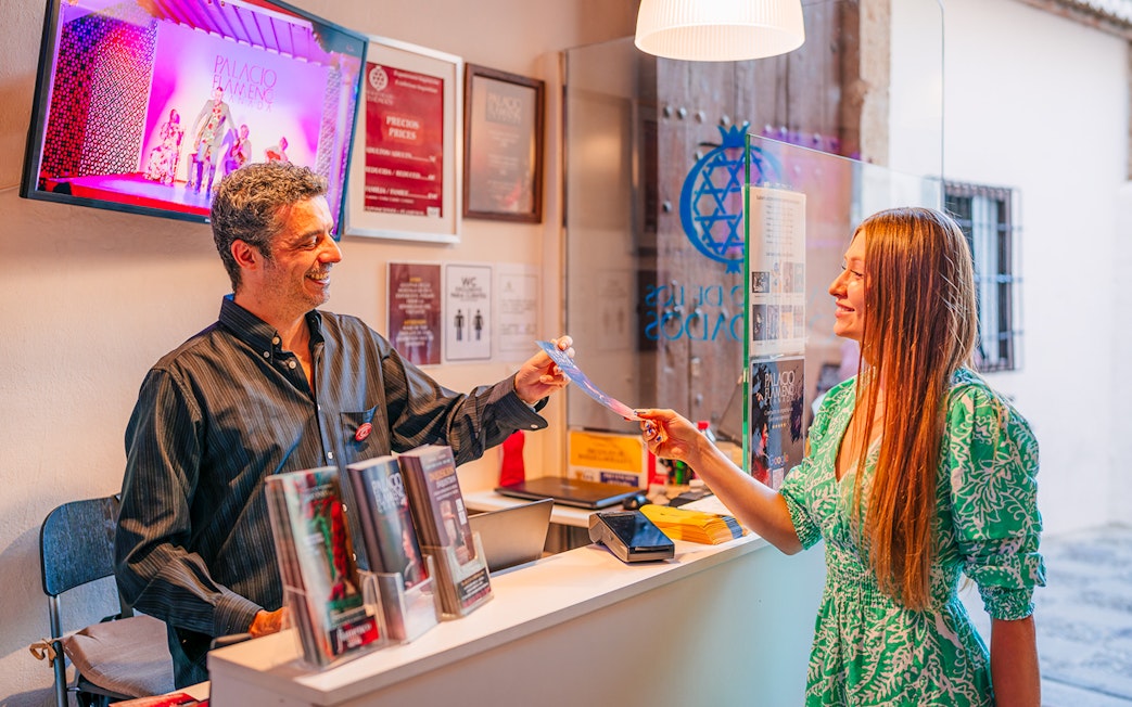 Receptionist handing ticket to visitor at Palacio de los Olvidados Flamenco Show.