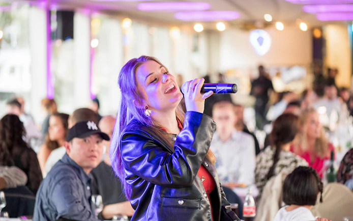 Singer performing on Le Diamant Bleu cruise with audience in background.