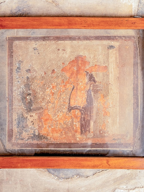 Framed ancient fresco with faded colors on a wall in Herculaneum, Italy.