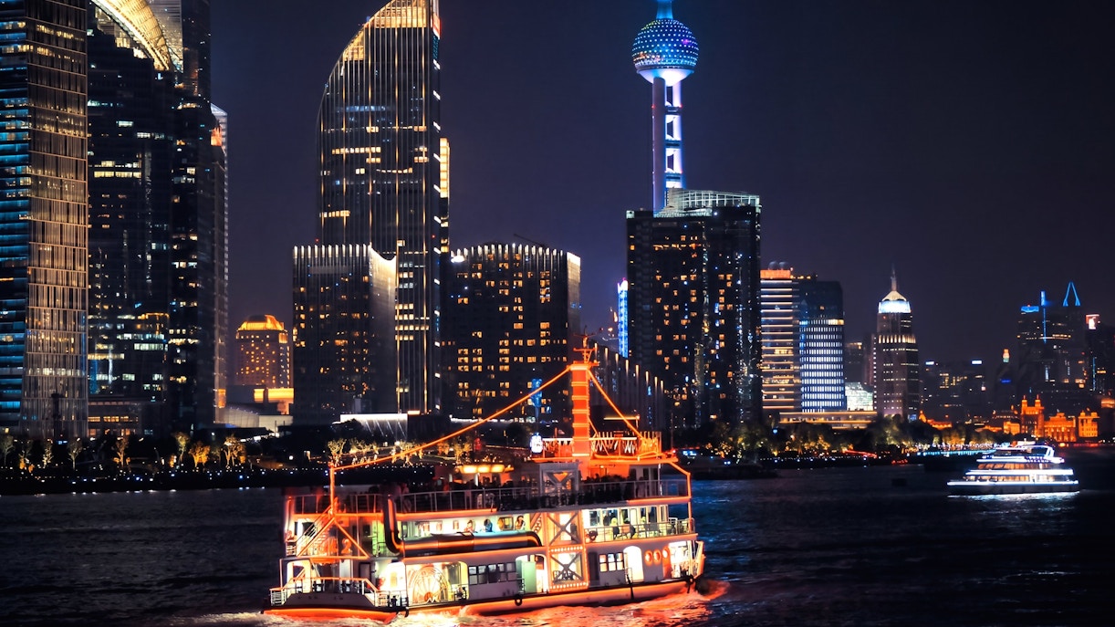 Illuminated cruise on Huangpu River with Shanghai skyline at night.