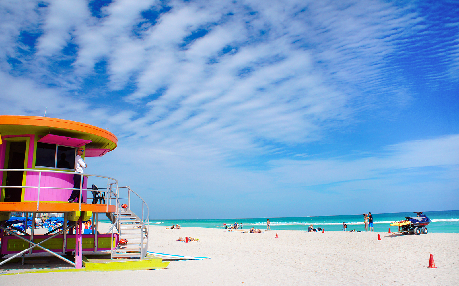 Colorful lifeguard tower on Miami Beach, Florida, with people enjoying the sandy shore.