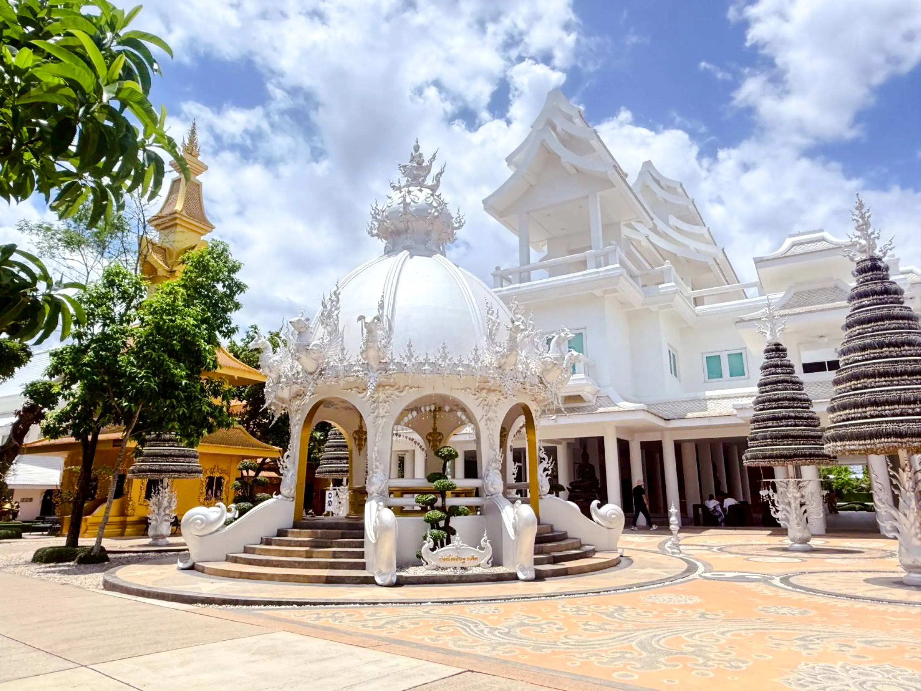 White temple pavilion with intricate carvings in Chiang Rai, part of Chiang Mai to Chiang Rai tour.