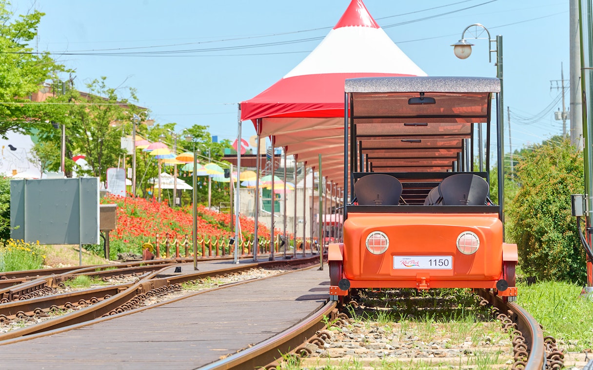 Orange Gangchon Rail Bike on tracks near station, South Korea.