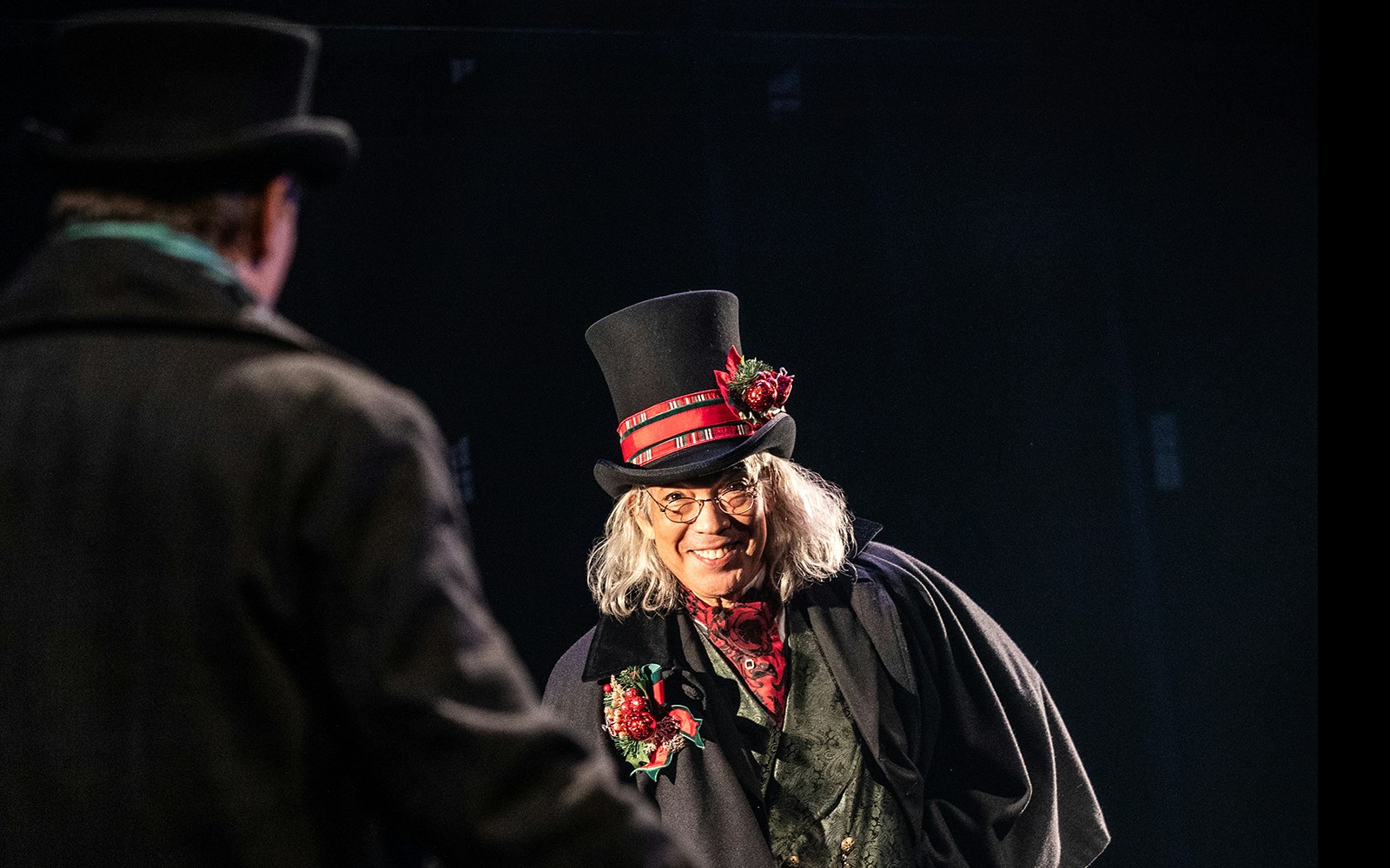 Character in Victorian attire with top hat in "A Sherlock Carol" performance.