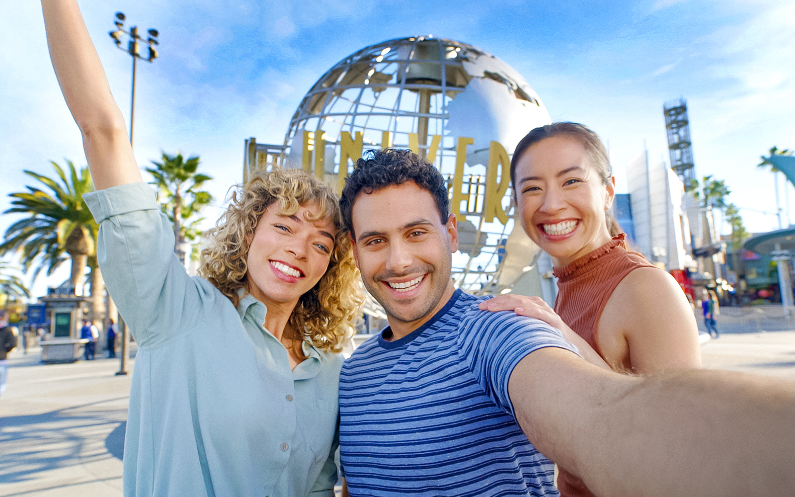Visitors smiling in front of the Universal Studios Hollywood globe.