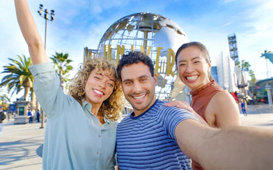 Visitors smiling in front of the Universal Studios Hollywood globe.