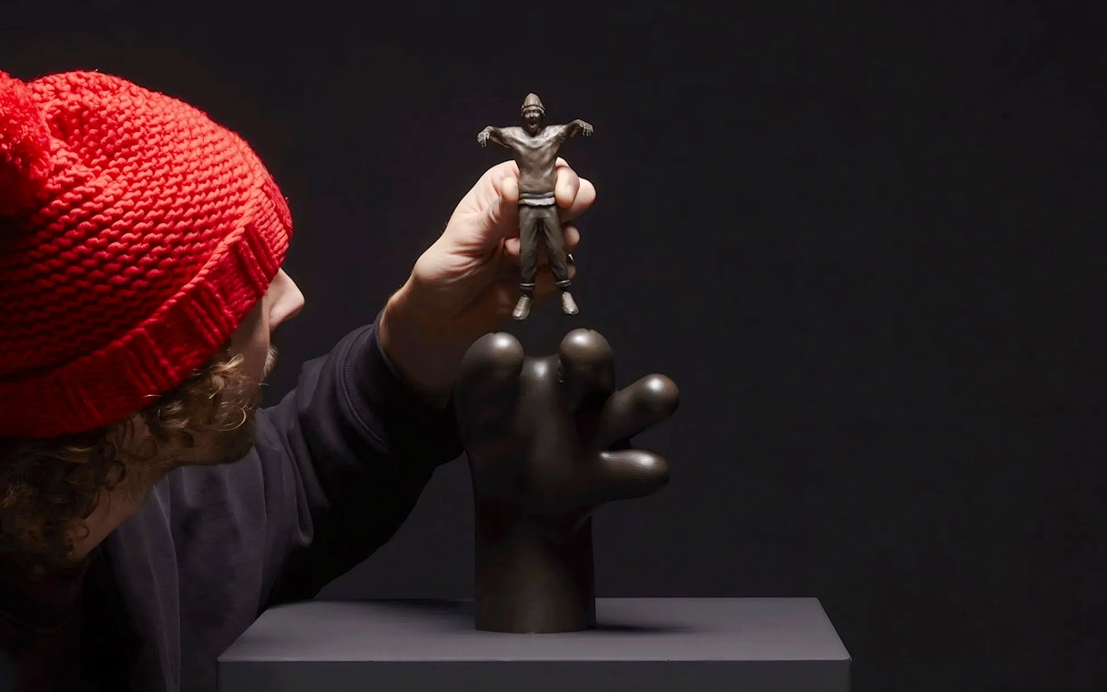 Hand holding a small sculpture by Frankey at Moco Amsterdam's Planet Positive Disruption exhibit.